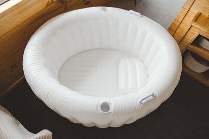 White inflatable birth pool on a dark surface with wooden side walls