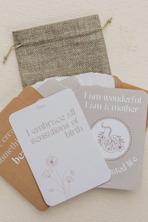 Set of birth affirmation cards with a drawstring bag on a light wooden surface