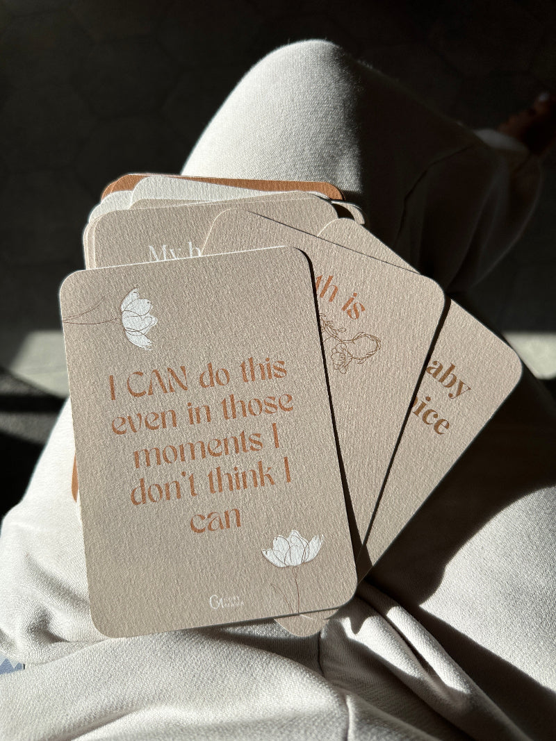 Set of birth affirmation cards held by a person with text on them.