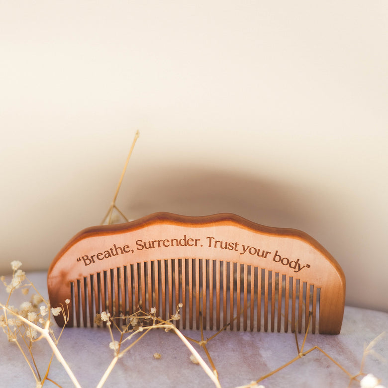 Wooden comb with engraved text on a soft surface with decorative elements
