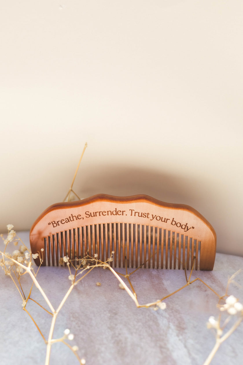 Wooden birth comb with engraved text on a soft surface with decorative elements