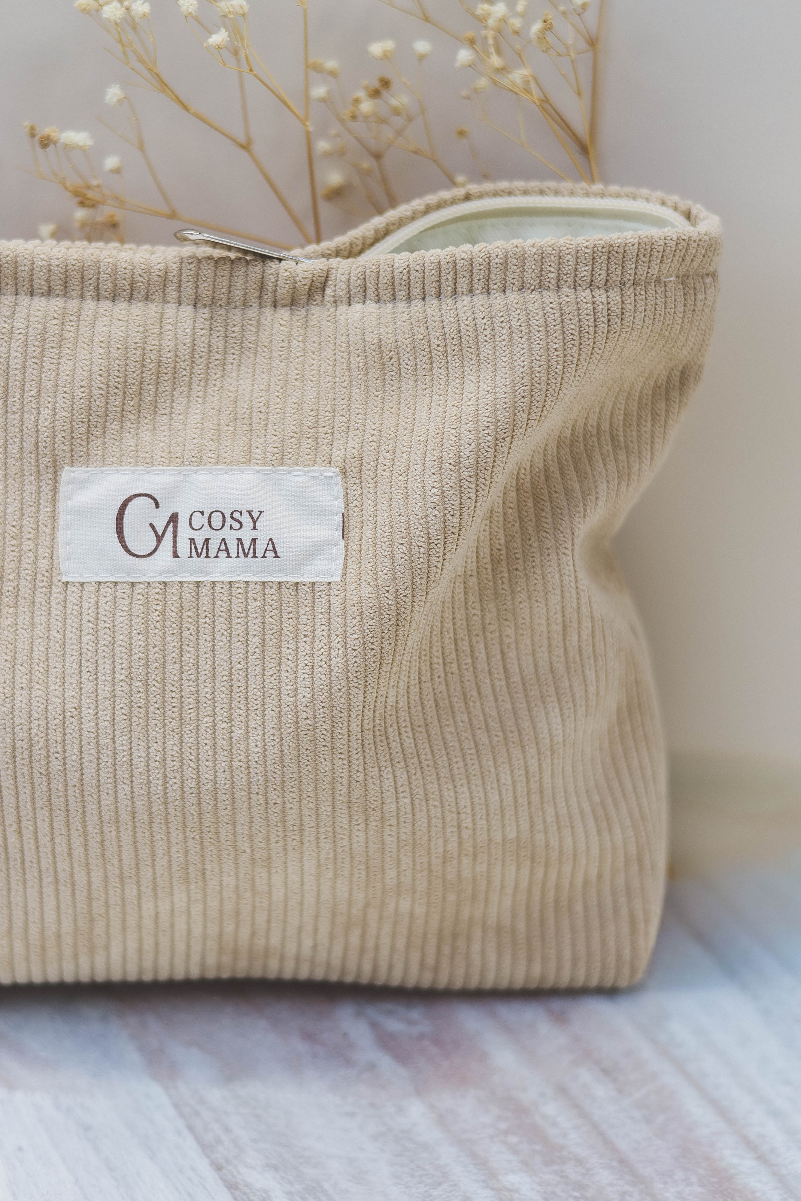 Beige corduroy bag with 'Cosy Mama' label on a light wooden surface.