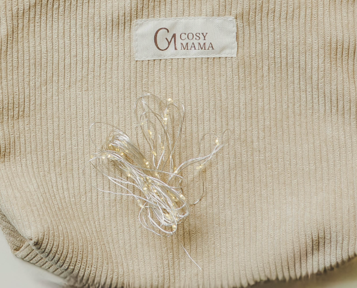 Beige textured fabric with Fairy Lights on it and 'Cosy Mama' label.