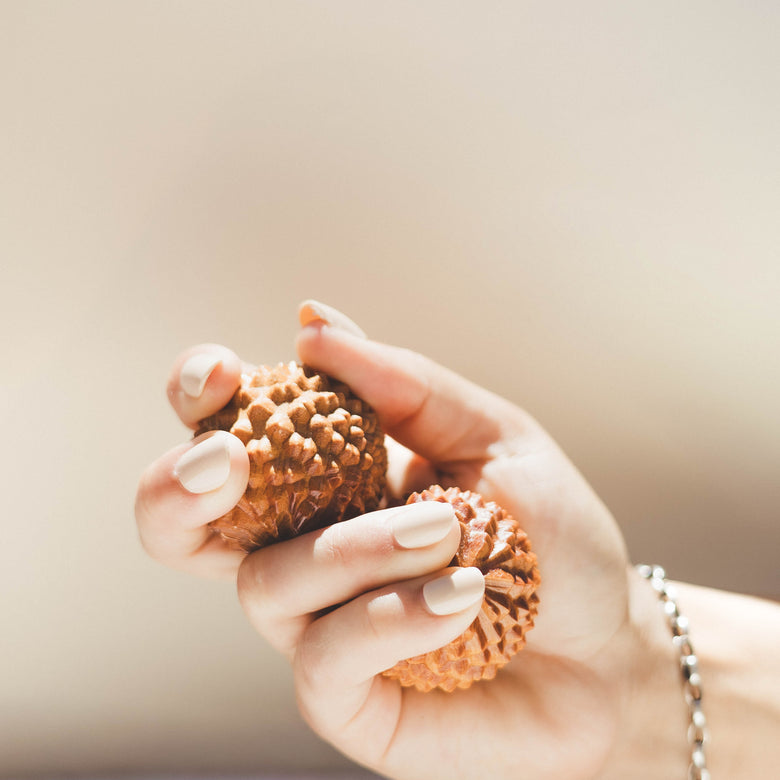 Hand holding two acupressure birth orbs against a neutral background
