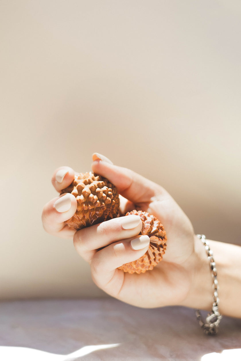 Hand holding two acupressure birth orbs against a neutral background