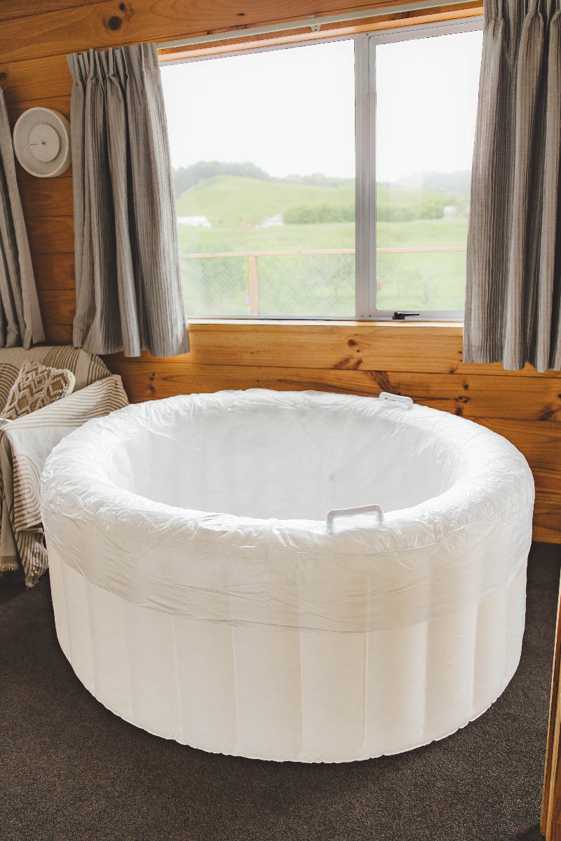 White inflatable birth pool a room with wooden walls and large window.