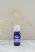 Bottle of AromaSense labour massage oil on a white surface with dried flowers in the background