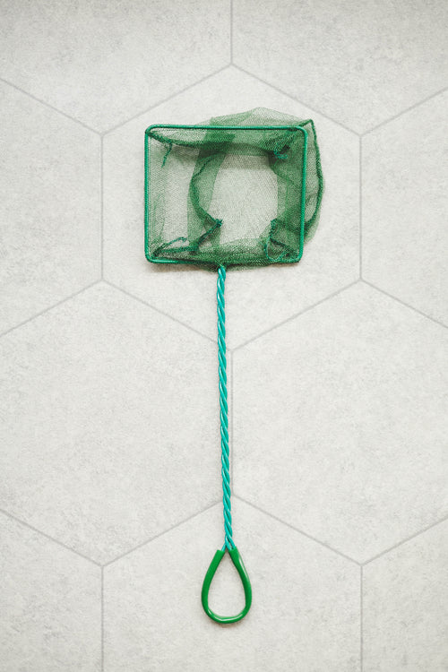 Green net with a handle on a light gray Lino floor
