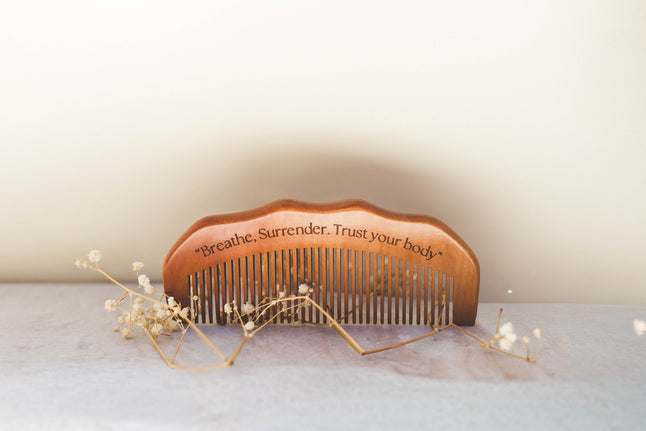 Wooden Birth comb with engraved text on a light background