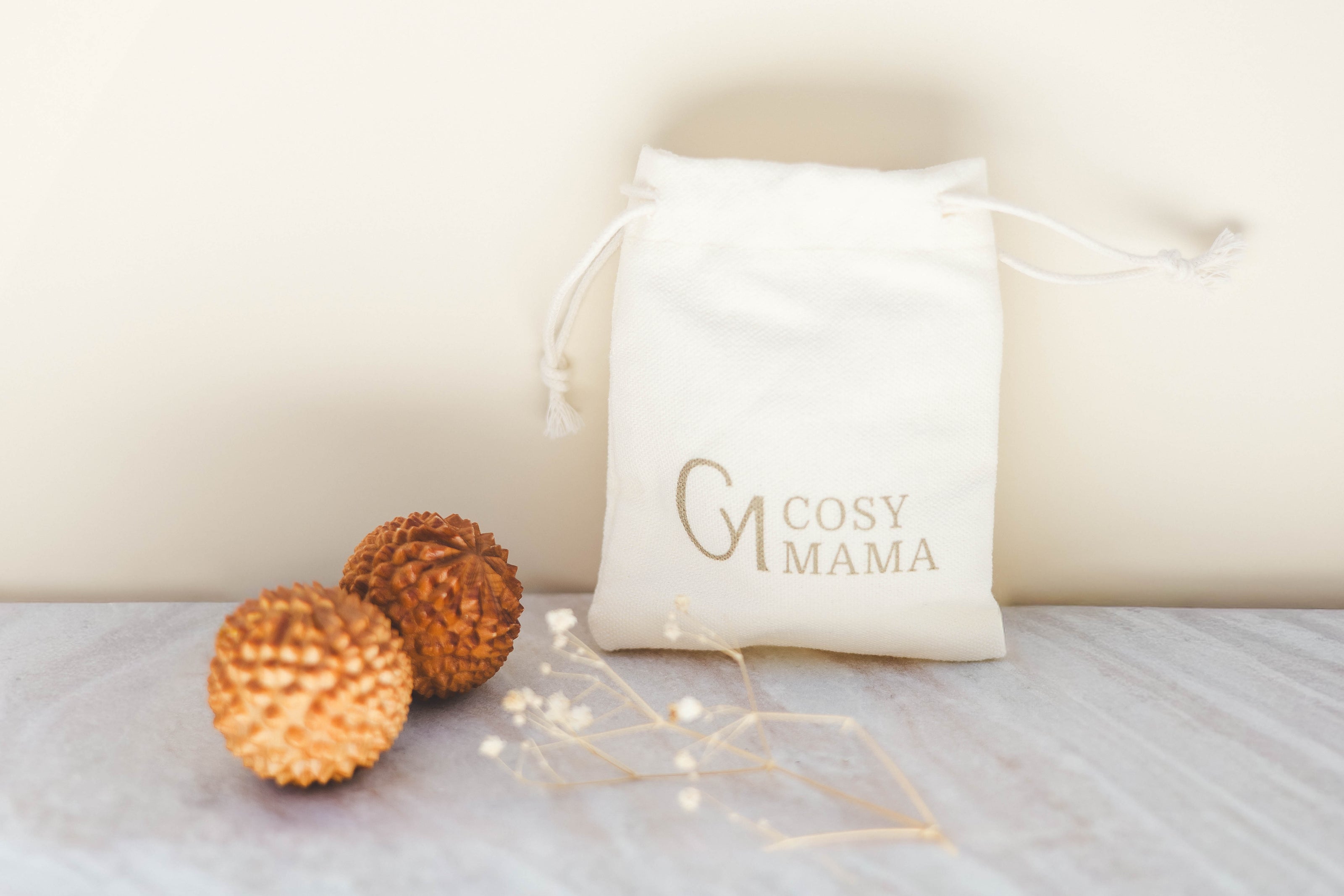 Cosy Mama Birth Orb pouch with decorative elements on a light background and Birth Orbs next to it