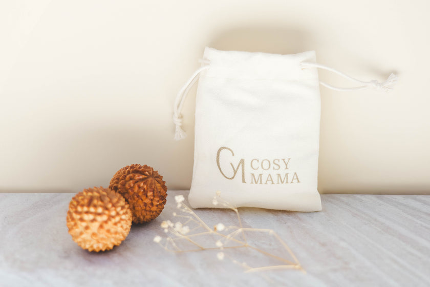 Cosy Mama Birth Orb pouch with decorative elements on a light background and Birth Orbs next to it