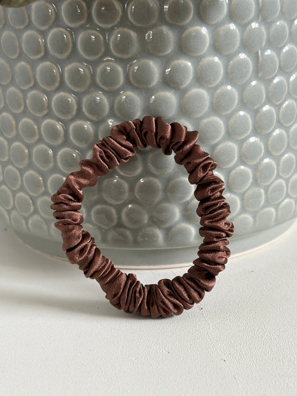 brown mulberry silk hair tie leaning against a post plant